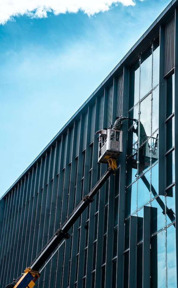 A young man cleaning the window standing on the lifter car